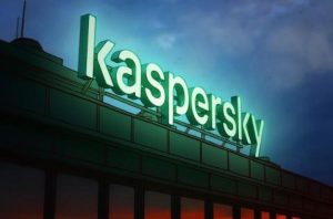 Rooftop lighted letter logo for Kaspersky. Illuminated green against a darkening evening sky.