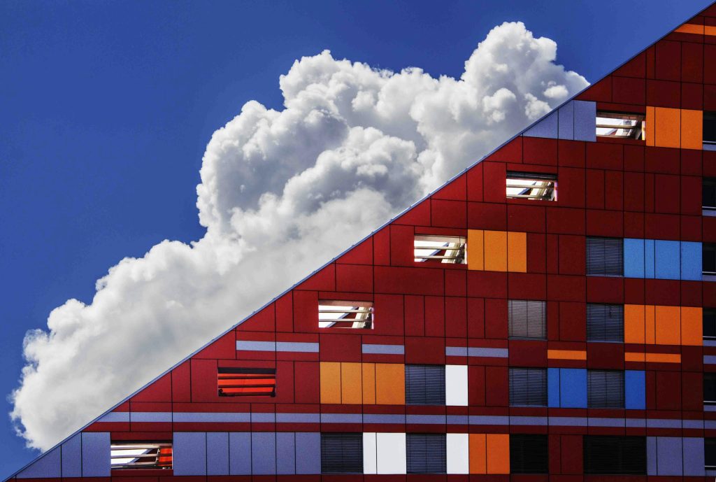 White clouds behind a building shaped at 45 degrees